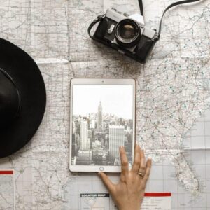 girl looking at a tablet with pictures of new york city, and a map, a black hat and camera