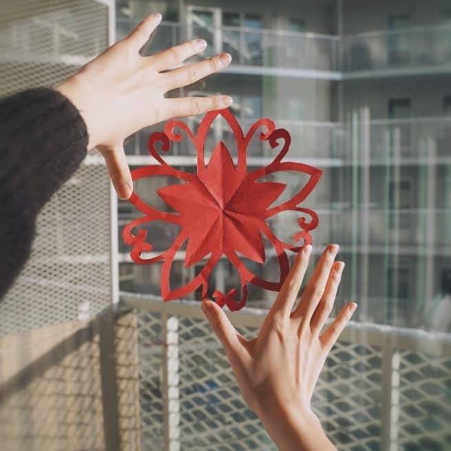 Red Chinese New Year cutting on a window framed by hands
