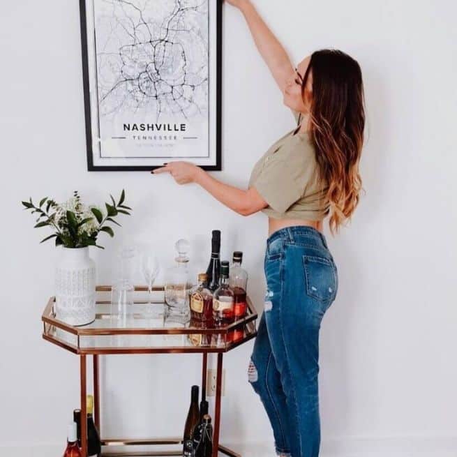 Glasswear on a bar cart with a custom poster of nashville