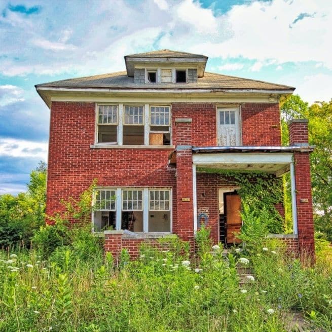 overgrown garden and abandoned red brick house