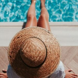 girl in hat sitting by the pool
