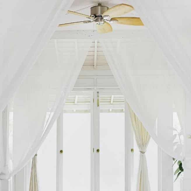 wooden ceiling fan in a white tropical bedroom