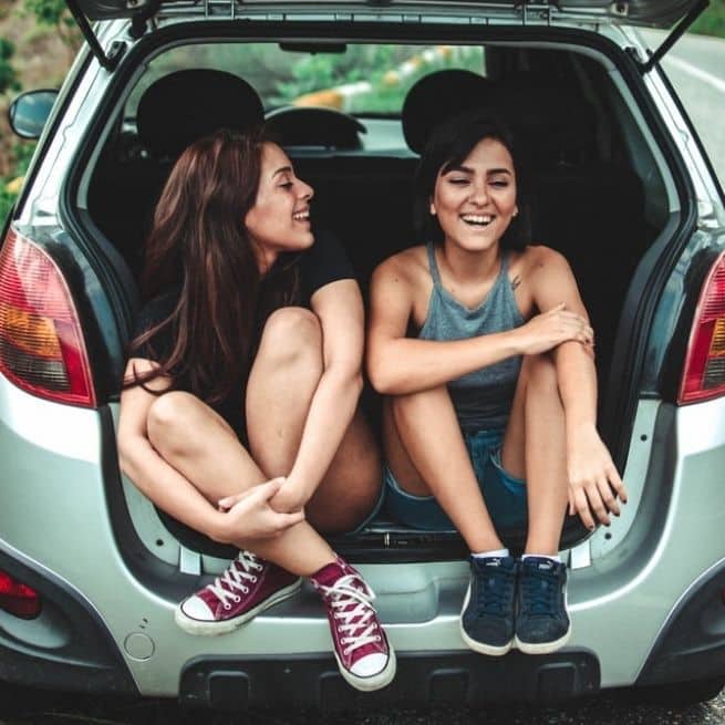 two friends sitting in the back of a car